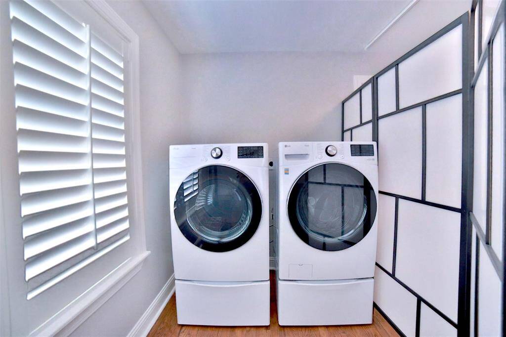 Bright and efficient laundry room featuring modern front-loading washer and dryer, enhanced by natural light from a shuttered window. this washer and dryer are set inside the extra room