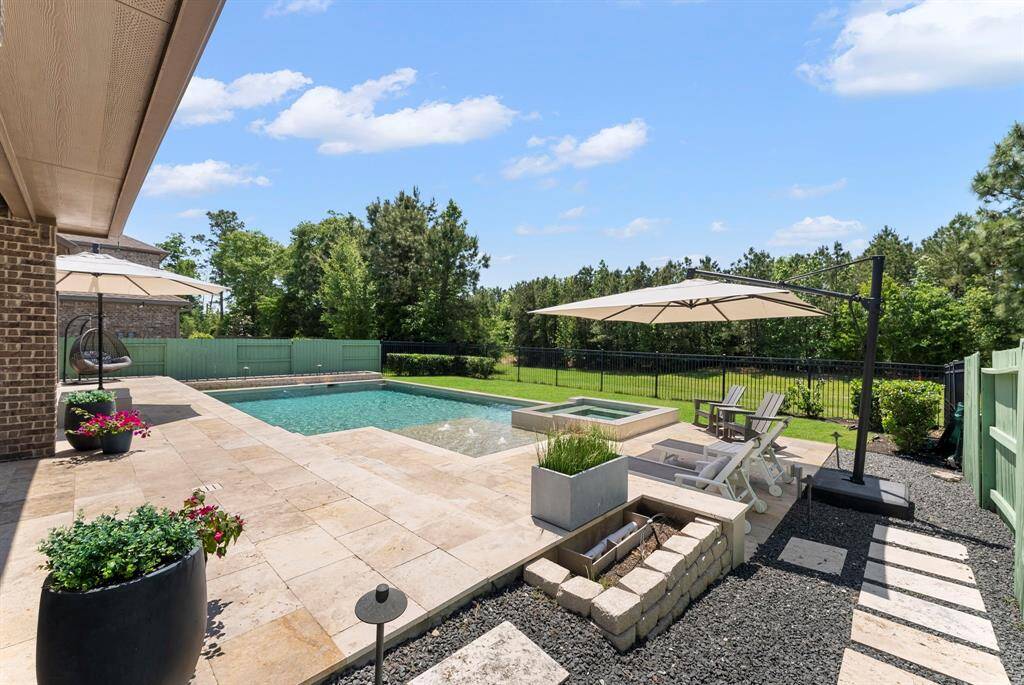 A modern designed pool/spa with tanning ledge and bubblers, surrounded by extra large travertine patio perfect for entertaining.