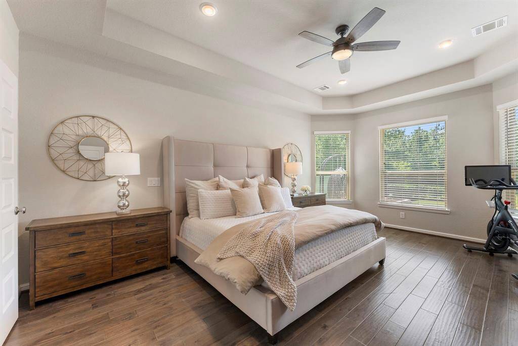 This spacious 1st floor primary bedroom features wood floors, a tray ceiling and extended conversation area at windows.