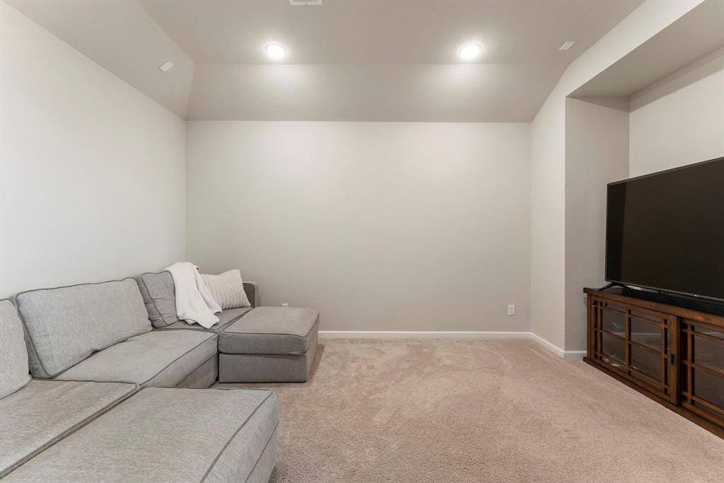 Media room with petite vaulted ceiling sits adjacent game room.