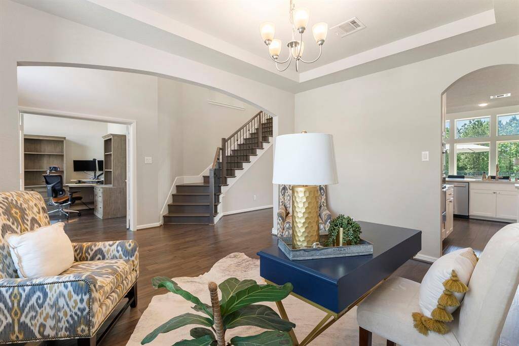 Natural light pours in from nearby windows, enhancing the open feel. An arched entryway leads to a modern kitchen, and a staircase offers access to the upper level.