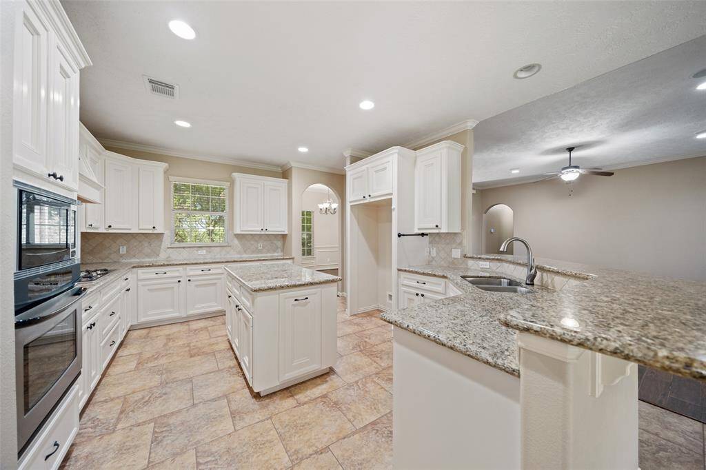The kitchen features a great layout with a central island, bar seating, and seamless flow into the breakfast and living areas.
