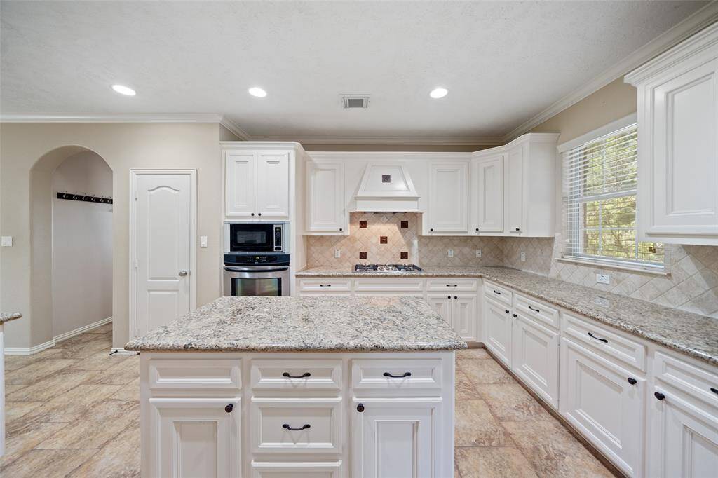Stylish and functional with a gas cooktop, decorative vent hood, and built-in ovens and microwave.