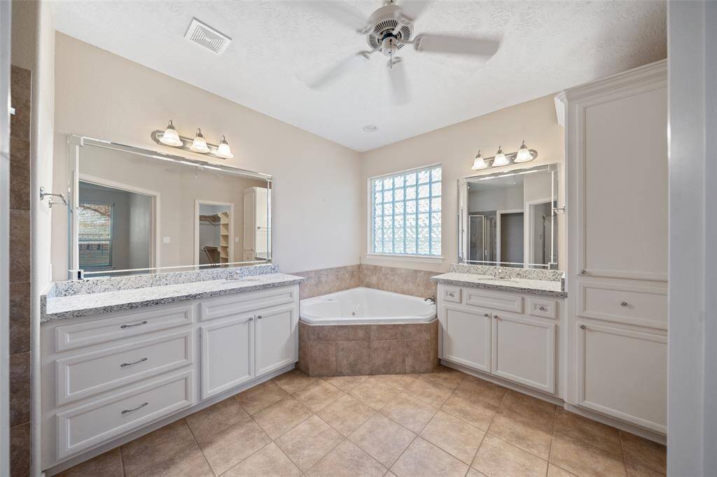 Dual vanities, granite counters, and a soaking tub highlight this clean and functional primary bath.