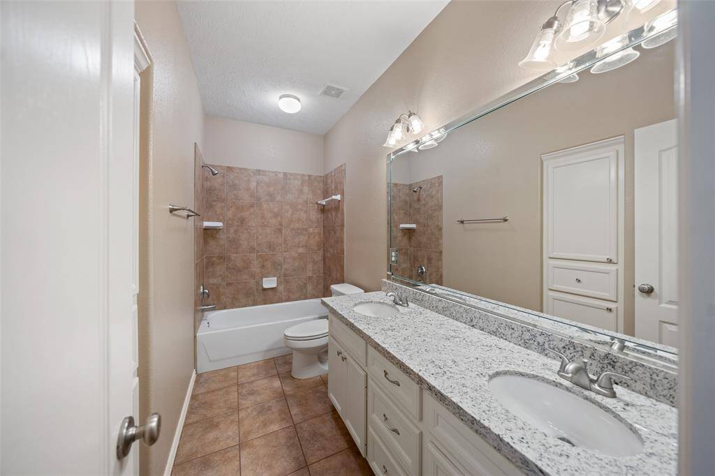 The secondary bath features a full shower/tub combo, dual sinks, and granite countertops — a smart setup for busy mornings.
