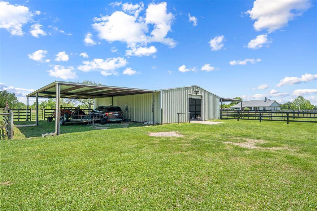This well-built barn features a durable metal exterior and a large attached carport, perfect for storing trailers, equipment, or parking your truck after a day out in the pasture.