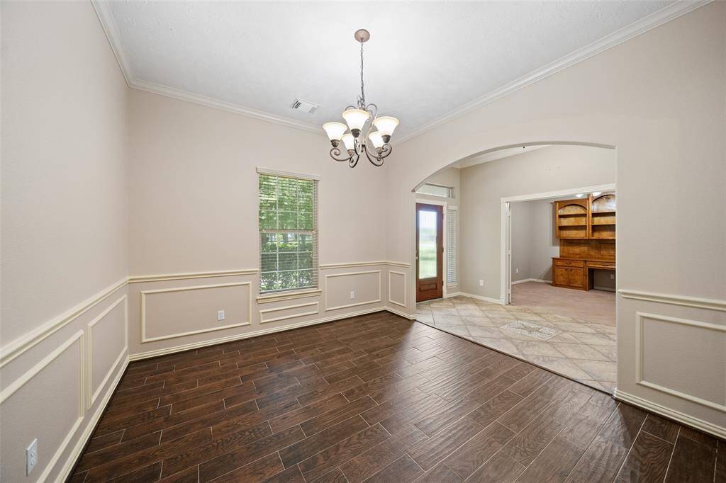 Host holiday dinners or cozy weeknight meals in this elegant dining room featuring wood-look tile flooring and classic wainscoting for timeless charm.