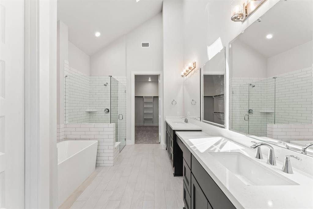 Spa-Like Primary Bath with Sky Light, Double Sinks, Vanity Area, Separate Shower, Freestanding Tub, and Linen Closet.