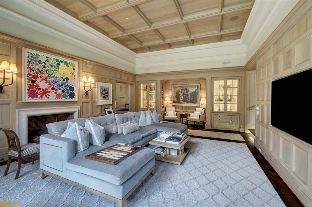 The Family Room. Pickled wood paneled walls and beamed ceiling. Limestone fireplace. Built-in glass front book and display shelving over drawer storage.