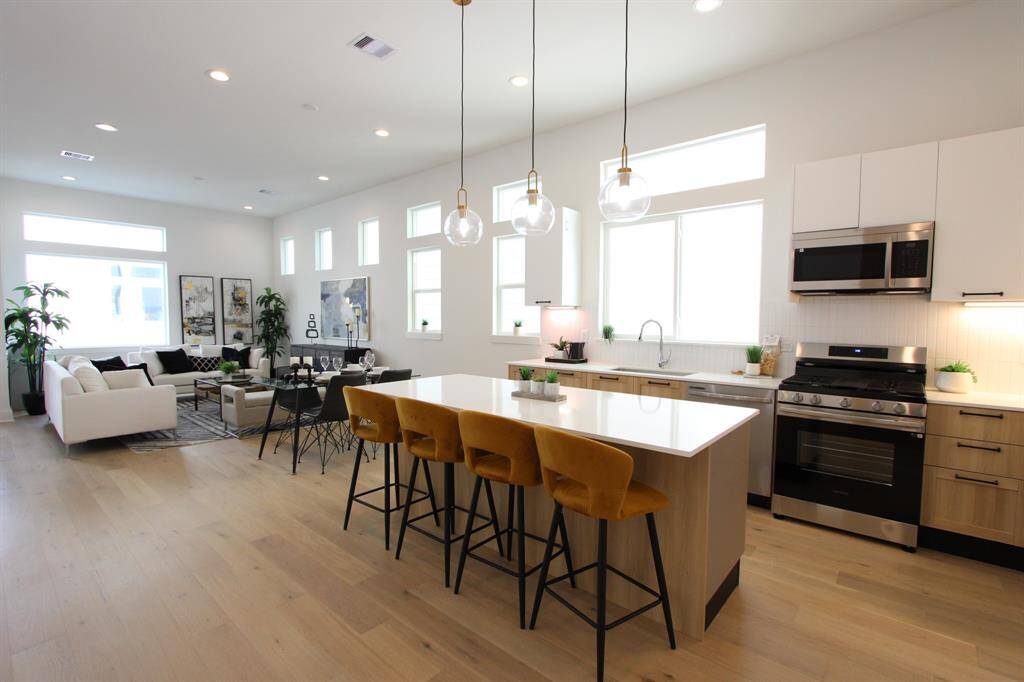 This open-concept space seamlessly blends the kitchen, dining, and living areas, featuring modern finishes, abundant natural light, and a stylish atmosphere perfect for entertaining or relaxing.