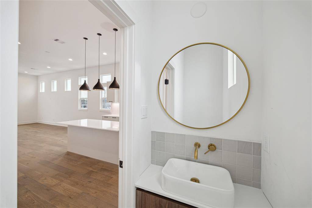 Chic powder room featuring a stylish round mirror, elegant fixtures, and sleek tile accents.