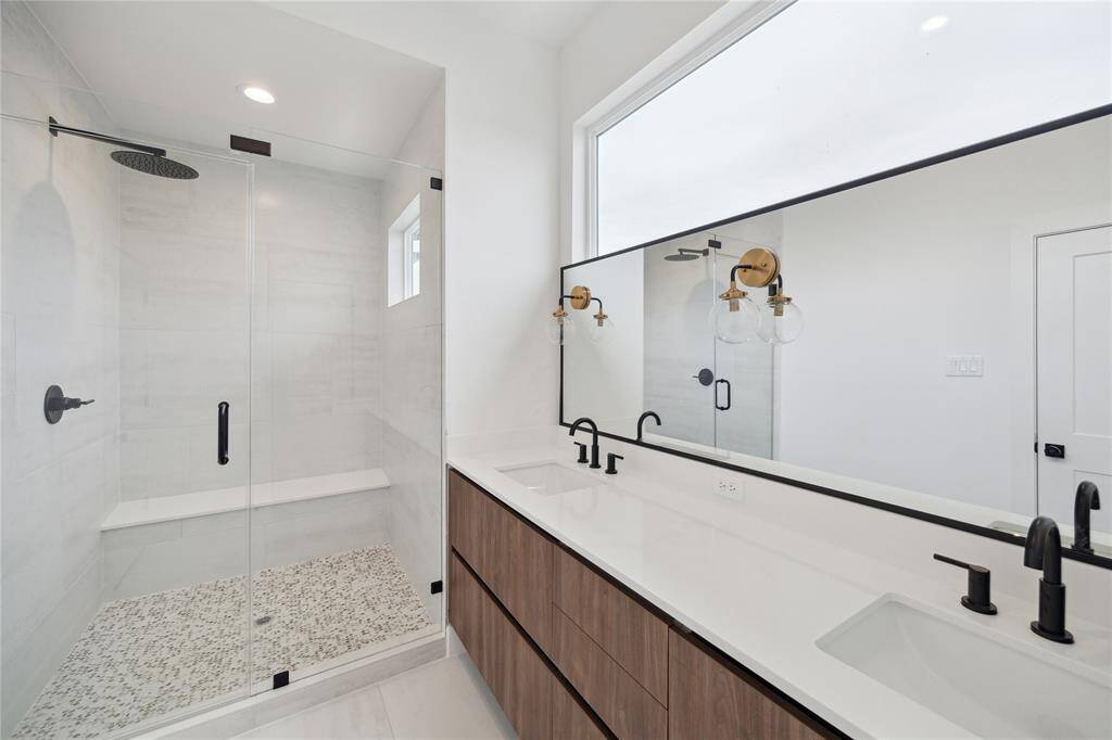 Elegant primary bathroom featuring a spacious glass shower, dual sinks, and modern fixtures, offering a luxurious retreat.