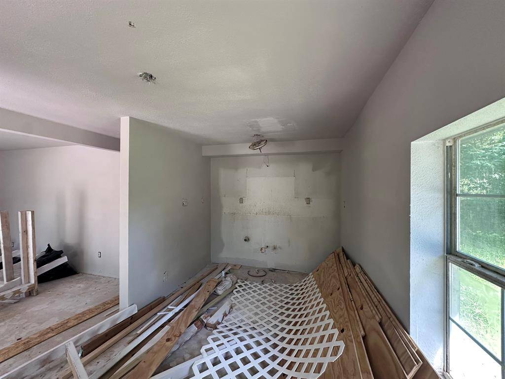 This room appears to be under renovation, with unfinished walls and construction materials present. It has a large window allowing natural light, and there's potential for customization.