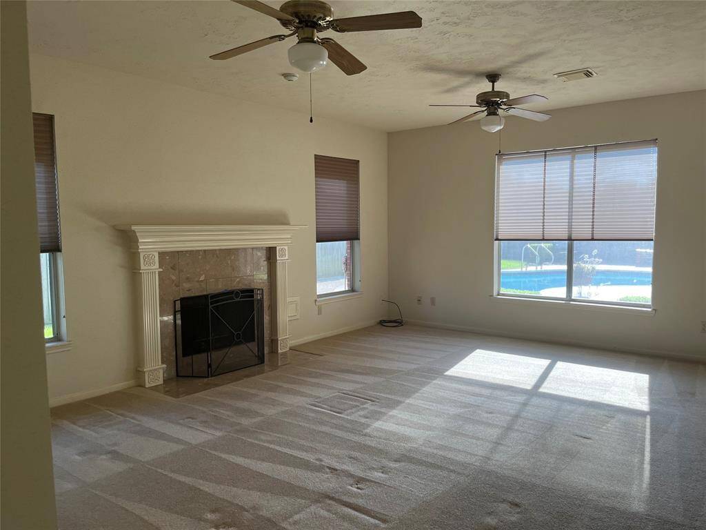 The spacious family room features a wood/gas fireplace and a large window offering views of the patio and pool—perfect for both relaxing and entertaining.