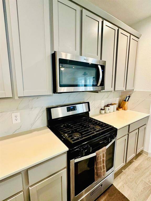 Modern kitchen with sleek light wood cabinets, a spacious island with a sink, and stainless steel appliances. The room features ample counter space, recessed lighting, and a stylish backsplash, creating a bright and inviting space for cooking and entertaining.