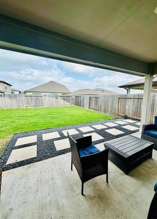 Spacious backyard featuring a well-maintained lawn, bordered by a wooden fence for privacy. A modern stone pathway adds style and functionality, perfect for outdoor activities or gatherings.