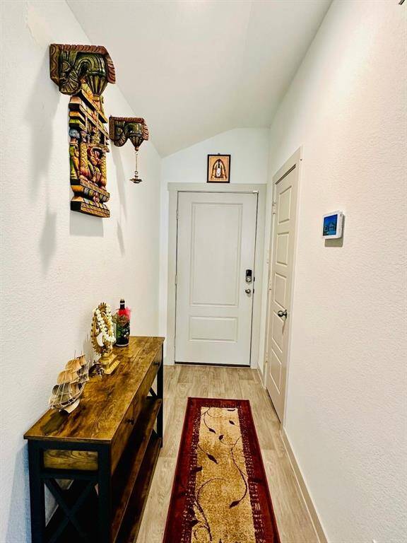 Inviting foyer with light walls and flooring. Features a decorative wooden console table and wall art, adding warmth and character.