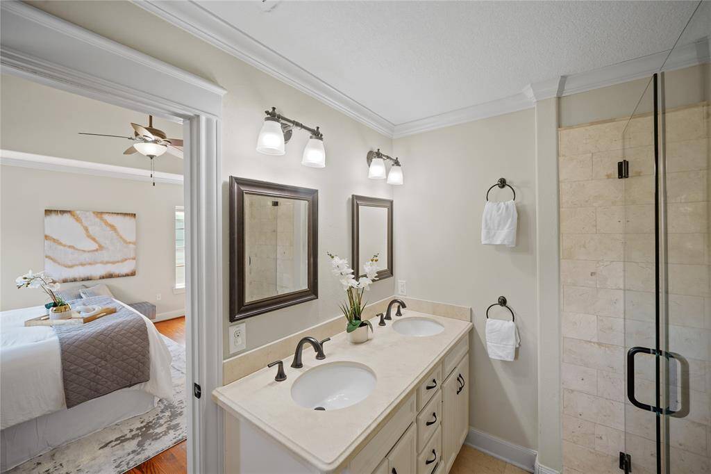 The ensuite bath features double sinks with sleek granite countertops and designer mirrors.