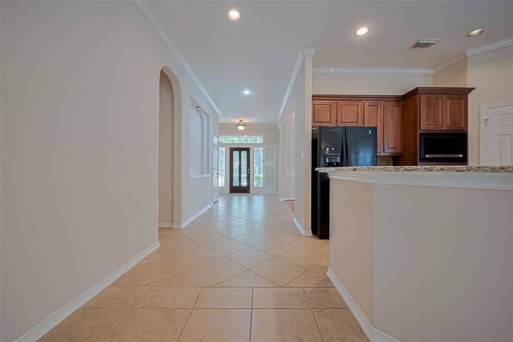 A view back toward the entryway reveals the home’s graceful layout. Light filters down the hallway and across the foyer, connecting each space with cohesion and brightness.