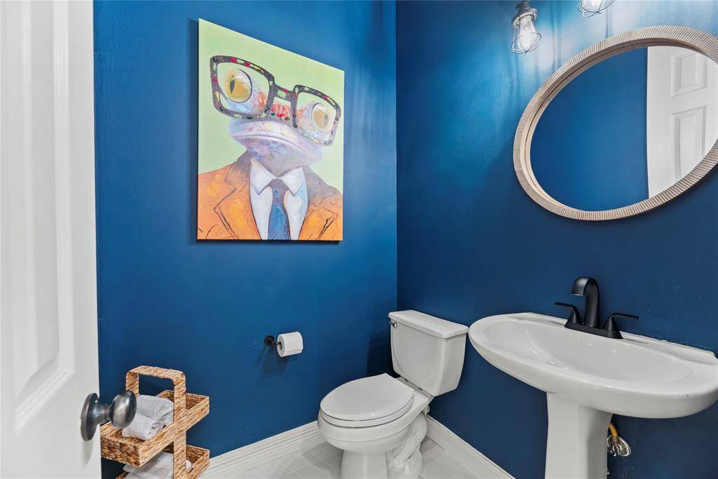 Chic and playful powder bath featuring bold navy walls, a modern pedestal sink, and designer Edison lighting.