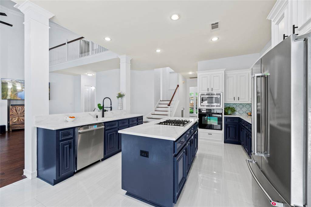 Functional kitchen layout with a large central island, farmhouse sink, stylish backsplash, and plenty of cabinetry for storage.