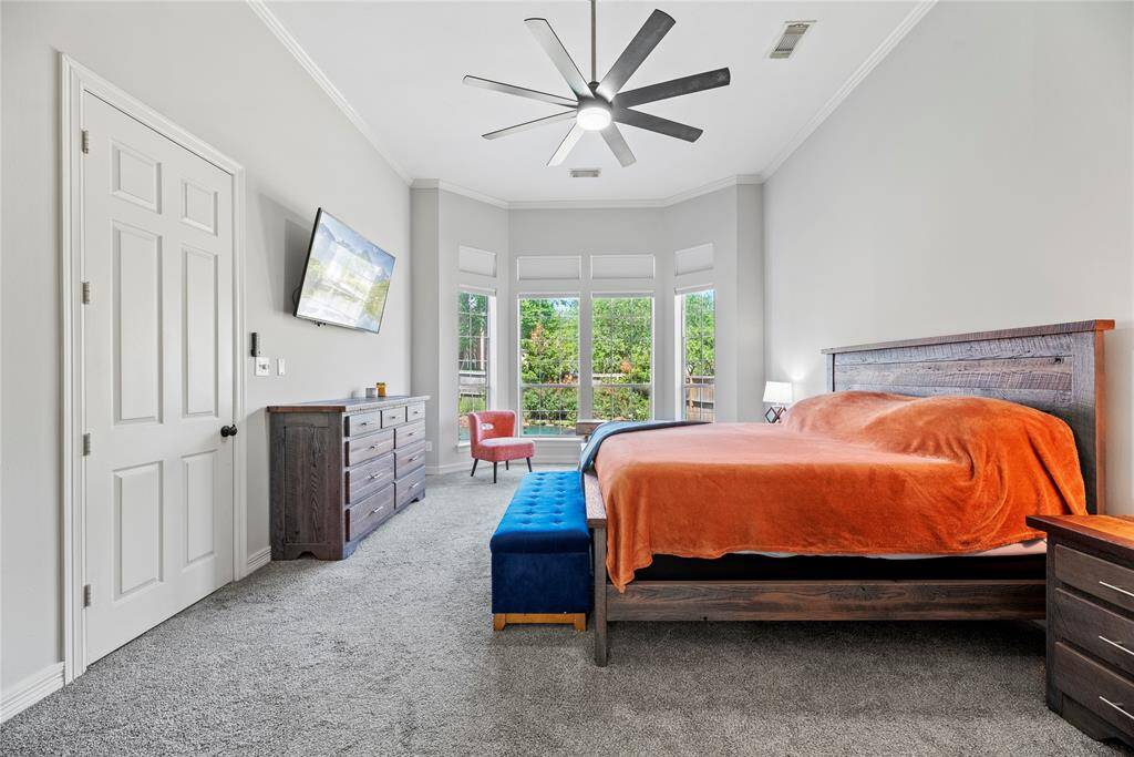 Spacious primary suite with plush carpet, a wall of bay windows overlooking the backyard oasis and lush landscaping, offering tranquil views.