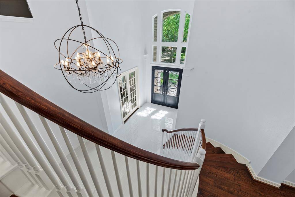 Beautiful view from the curved staircase, highlighting the soaring ceilings, large picture windows, and striking architectural design.