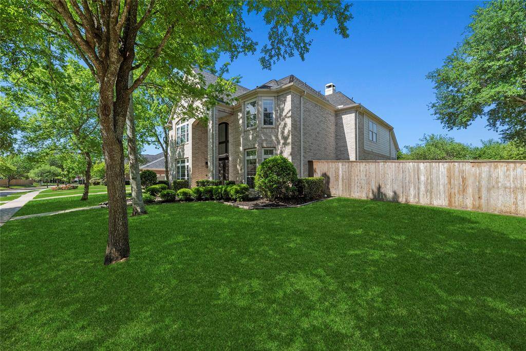 Side angle view of the expansive front and side yards, showcasing the corner lot’s spaciousness and the home’s stately presence.