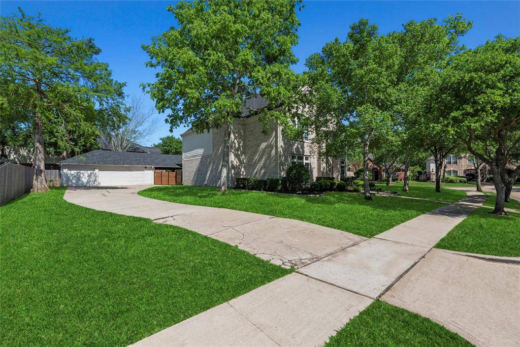 Long, curved driveway leading to the detached 3-car garage, offering plenty of parking space and surrounded by lush greenery.