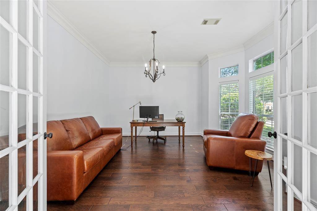 Versatile home office or study with French doors, hardwood flooring, and large windows bringing in an abundance of natural light.