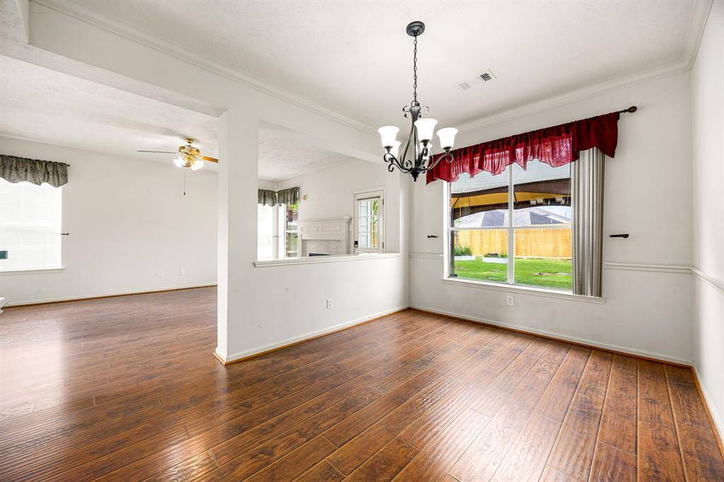 Engineered hardwood flooring carries from the living room into both the formal dining/flex space and the downstairs primary bedroom.