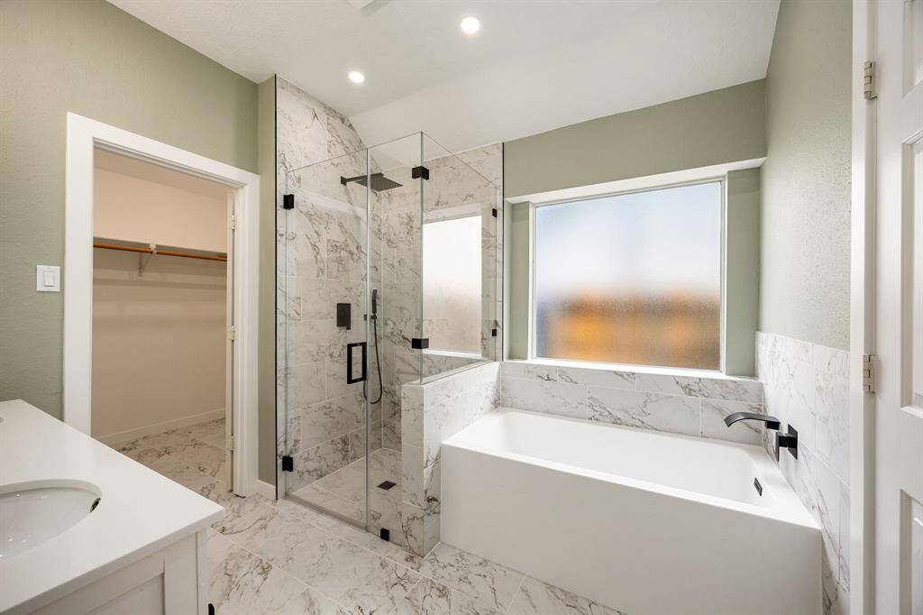 Updated primary bathroom features a soaker tub, stand alone shower,  double sinks and a large walk-in closet.