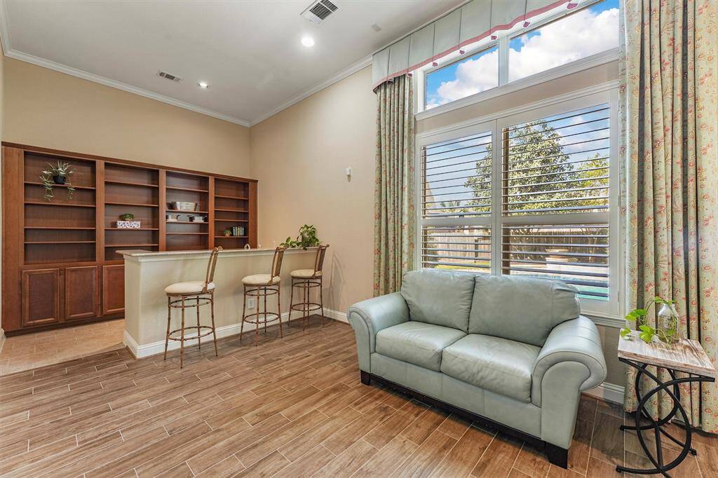 This bright, open bonus space features wood-style tile flooring, a stylish bar with shelving, bar sink and equipped for wine fridge. Large windows with plantation shutters offer great natural light and pool views, making it ideal for relaxation or entertaining.