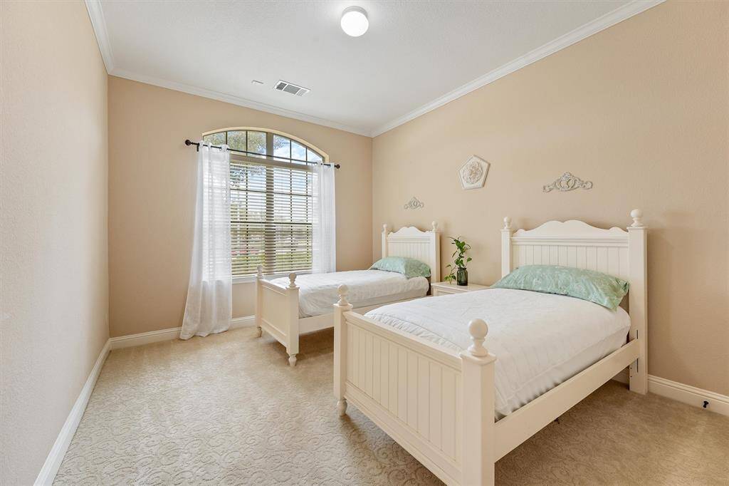 Secondary bedroom #1 - This cozy bedroom features two twin beds with elegant headboards, soft beige walls, and a large arched window with sheer curtains, allowing natural light to brighten the space.