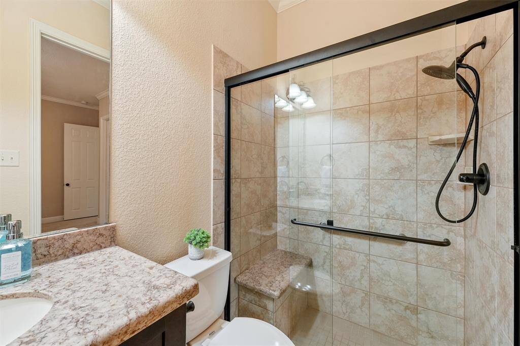 This bathroom features a modern glass-enclosed shower with a tiled interior and built-in seat and handrail.