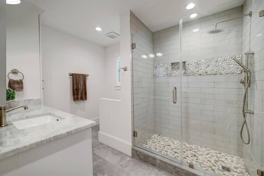 Downstairs Full bathroom has custom cabinetry and large linen closet for storage. Walk in shower perfect for guests or if you add a pool, a easy access to backyard.