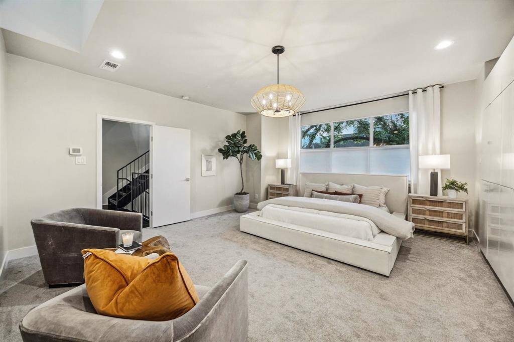 [Primary Bedroom 18 x 18] On third floor - features a natural, rattan style chandelier, shades and custom built-in closet storage.