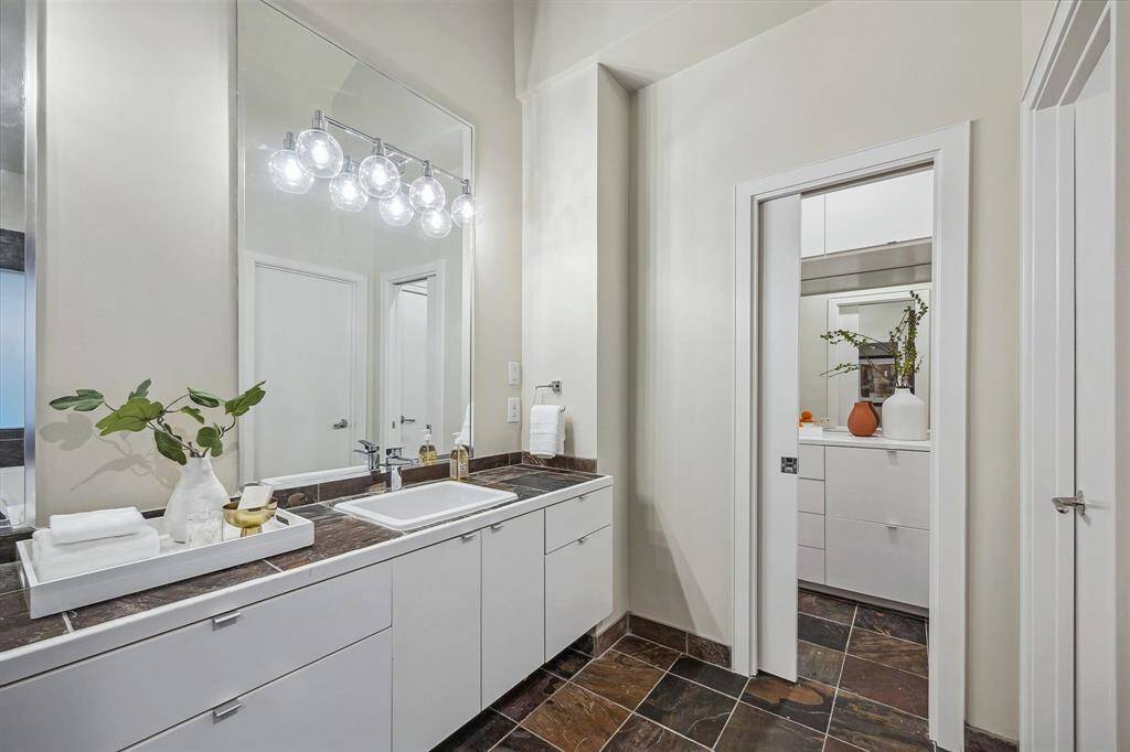 [Primary Bath 16 x 12] Custom cabinetry in primary bath with extra storage and hidden laundry area. Vanity area with storage between bedroom and bathroom.