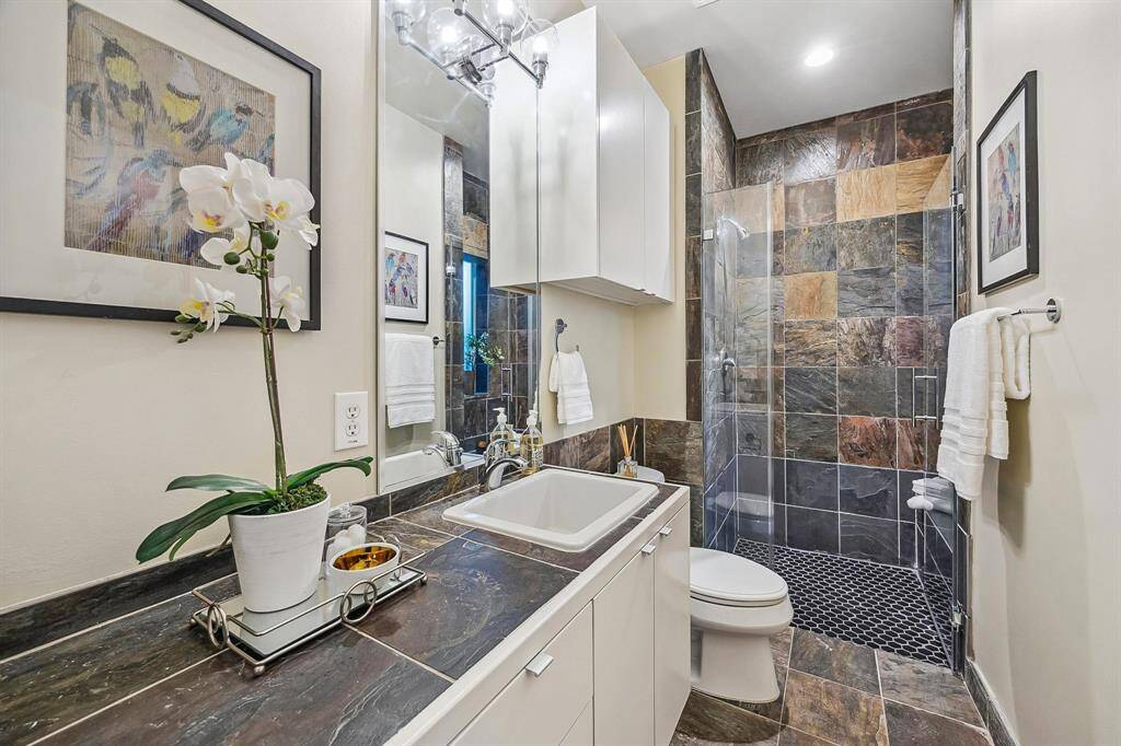 [First Level Ensuite Bath] Features frameless shower door with bench seat.  Great storage.
