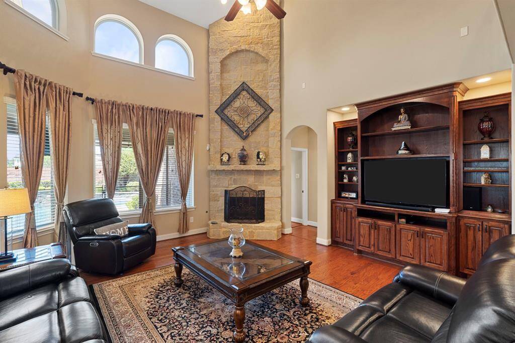 The family "Great Room" is the heart of the home, featuring a magnificent stone fireplace and expansive windows that offer tranquil views of the private backyard and pool area.