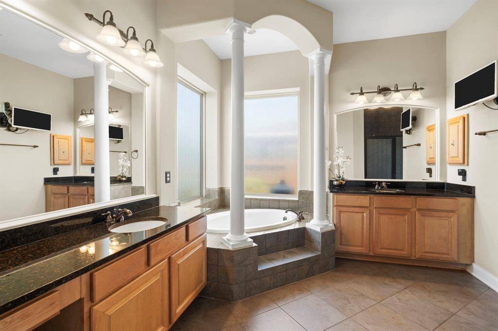 The ensuite primary bathroom is designed for ultimate relaxation with a jetted soaking tub, a separate walk-in shower, two vanity areas, and a large walk-in closet.