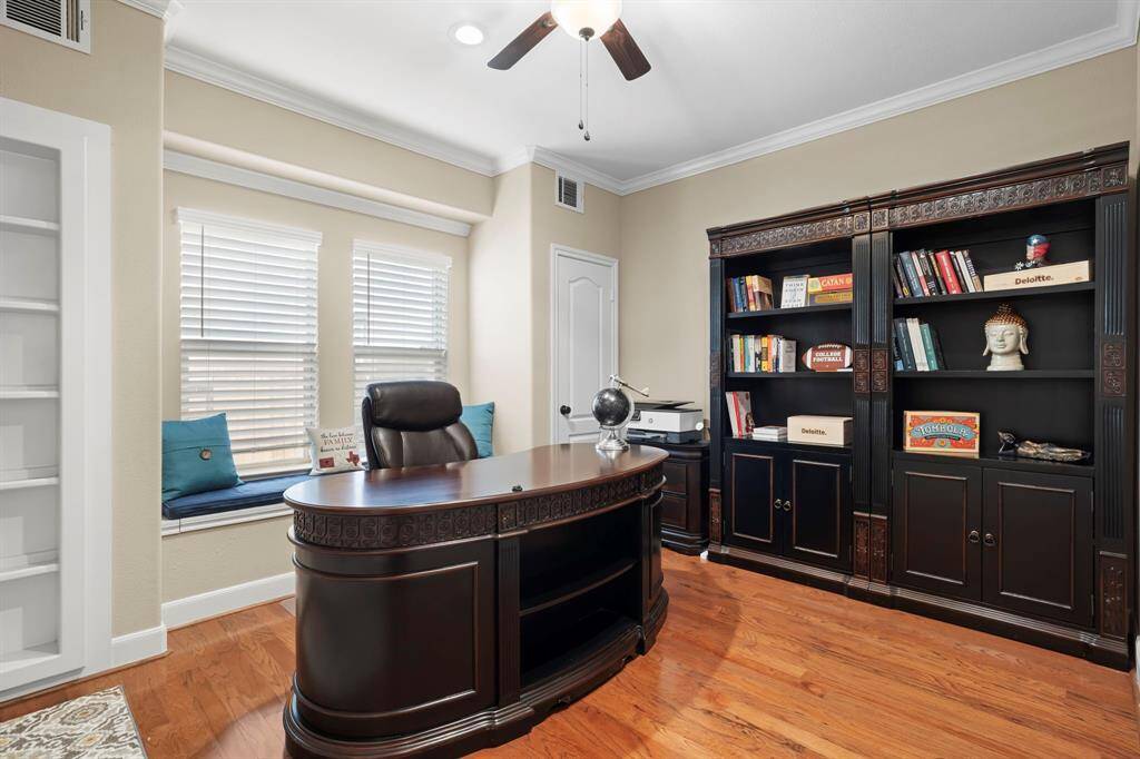 The first-floor home office, which can also serve as a fifth bedroom, features wood flooring, a walk-in closet, built-in bookshelves with a hidden door, and a charming built-in window seat.