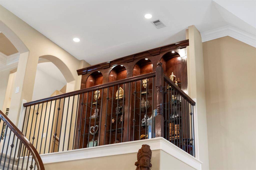 A built-in custom mahogany bookshelf with glass shelves offers the perfect space to showcase art, collections, or decorative pieces with style and sophistication.