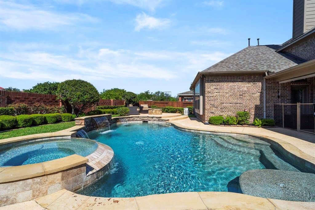 Gradual step entry heated pool features waterfalls, spa, and a Baja shelf.