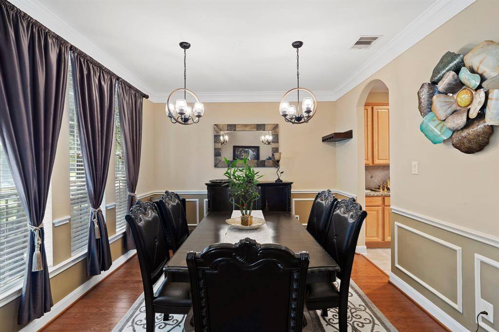 The dining room is elegantly appointed with matching pendant chandeliers, classic chair and crown molding and rich wood flooring.