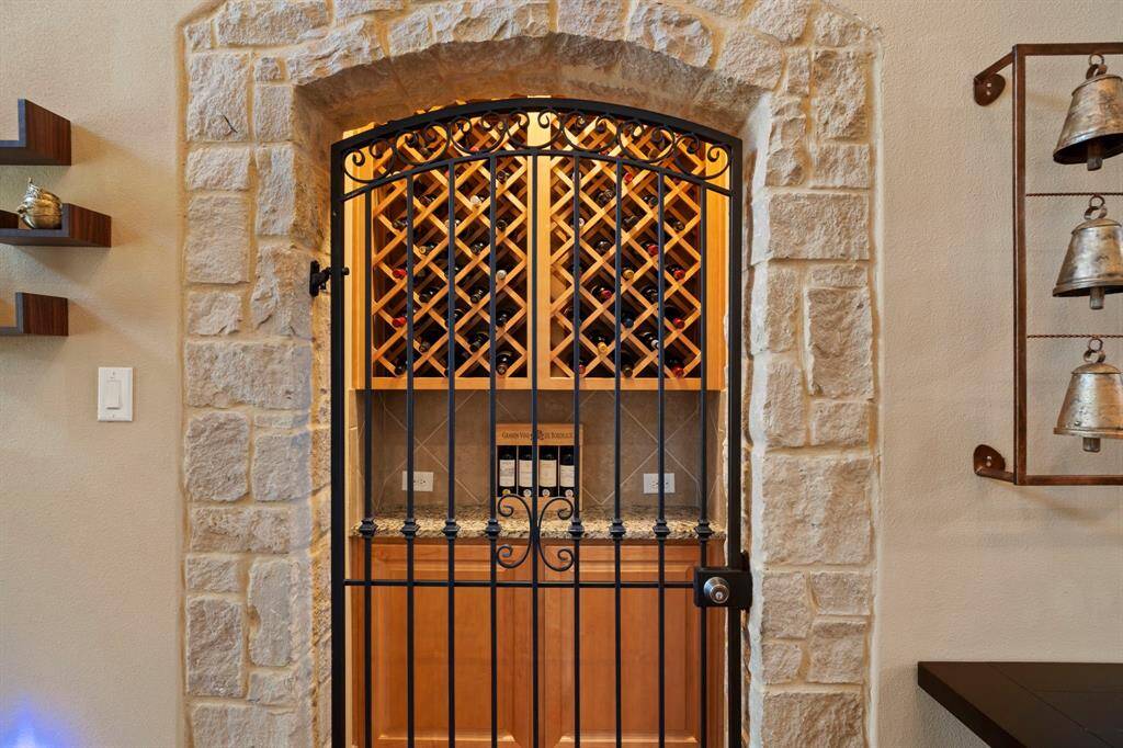 A private arched stone wine cellar, secured by a wrought iron gate, adds a touch of sophistication and exclusivity to the home.