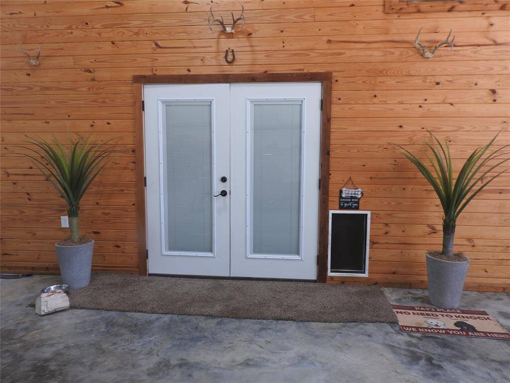 100% Custom Bardominium-Entryway with French Doors & Blinds inserted in the glass. Doggie Door to the right side. Concrete Flooring. Entire Barndominium is completely enclosed under a huge carport.