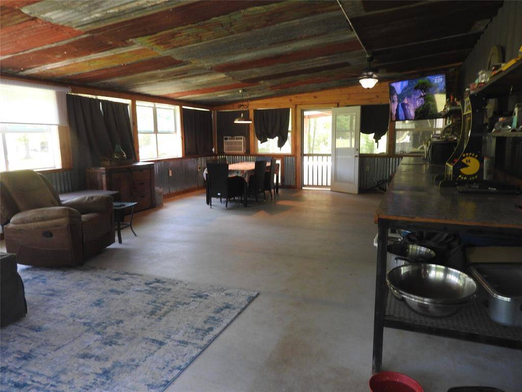 Outdoor Porch Area, but enclosed from the weather. The right side has a long bench used as a bar. Great Family Room with access to exterior yard, doggie door, wide space for entertainment.