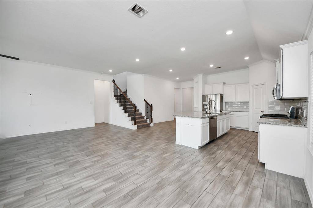 The heart of the home is the expansive open-concept living area, where natural light floods in through oversized windows, creating a warm and inviting atmosphere.