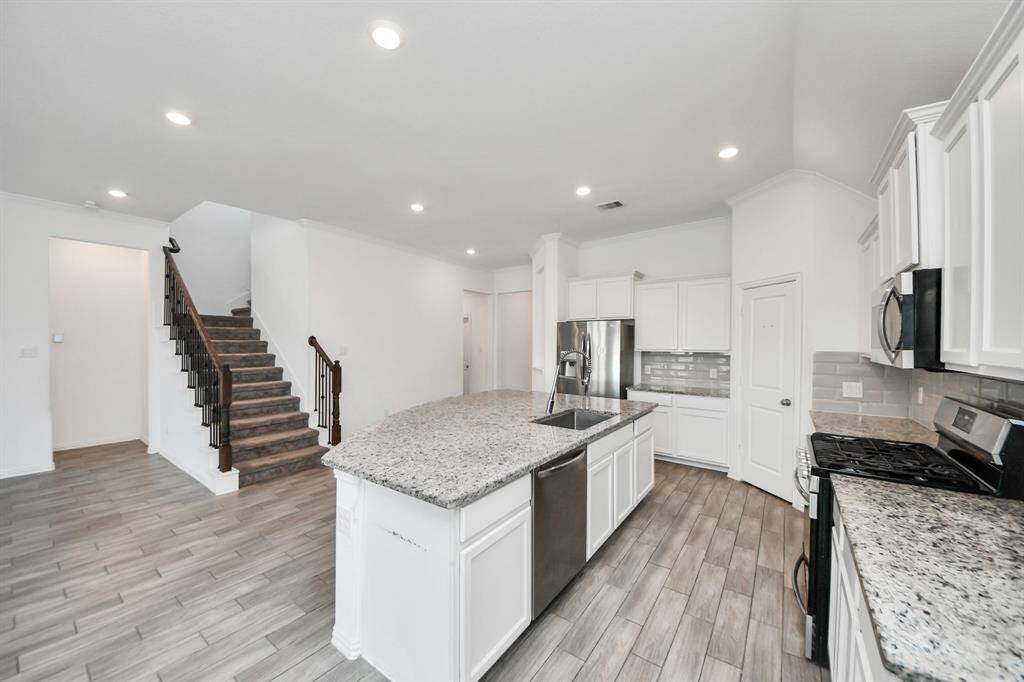 Just beyond the island, the kitchen opens directly to the living room, where tall ceilings and large windows create a light-filled and airy space.